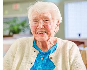 A smiling woman resident sitting in a chair.