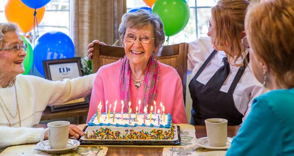 A smiling woman resident celebrating her 100th birthday with friends and staff.