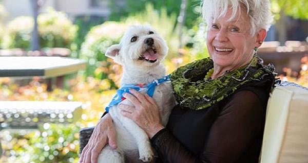 Smiling resident holder her white dog