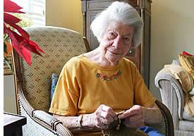 A smiling woman resident sitting on a chair in her apartment.