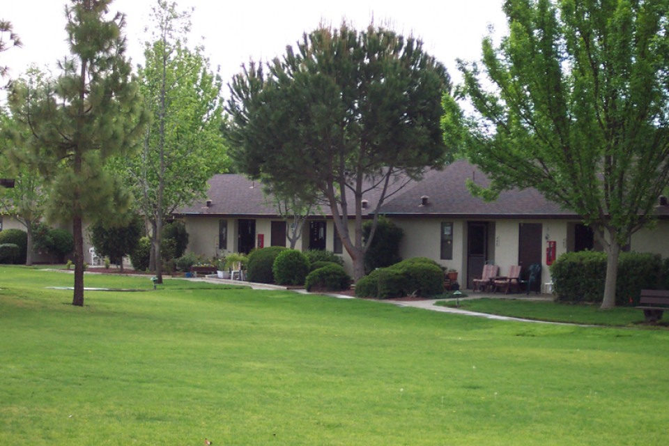 Exterior of Eskaton Kennedy Manor's apartments with beautiful trees and green lawn.