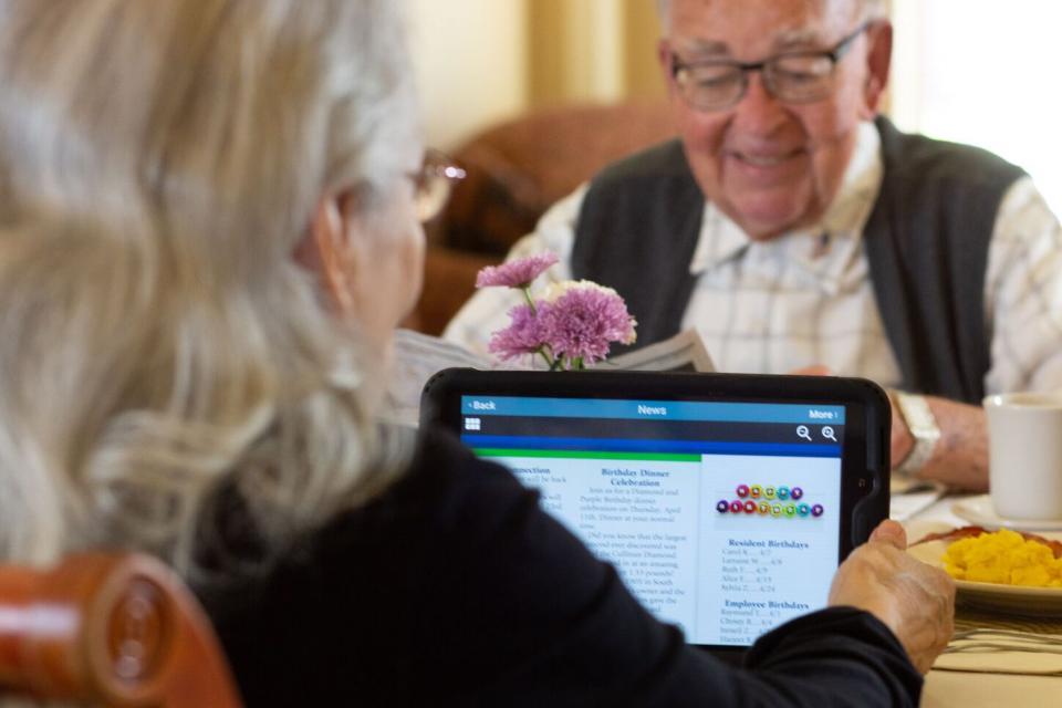 Two residents, a woman view events community events on her iPad and a man reading the paper.