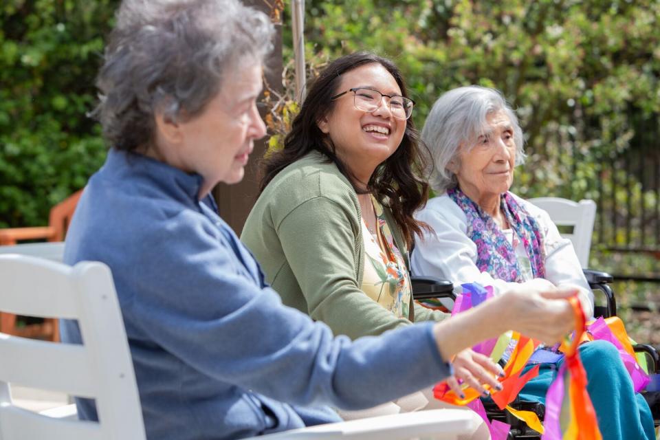 Three smiling women sitting outside.