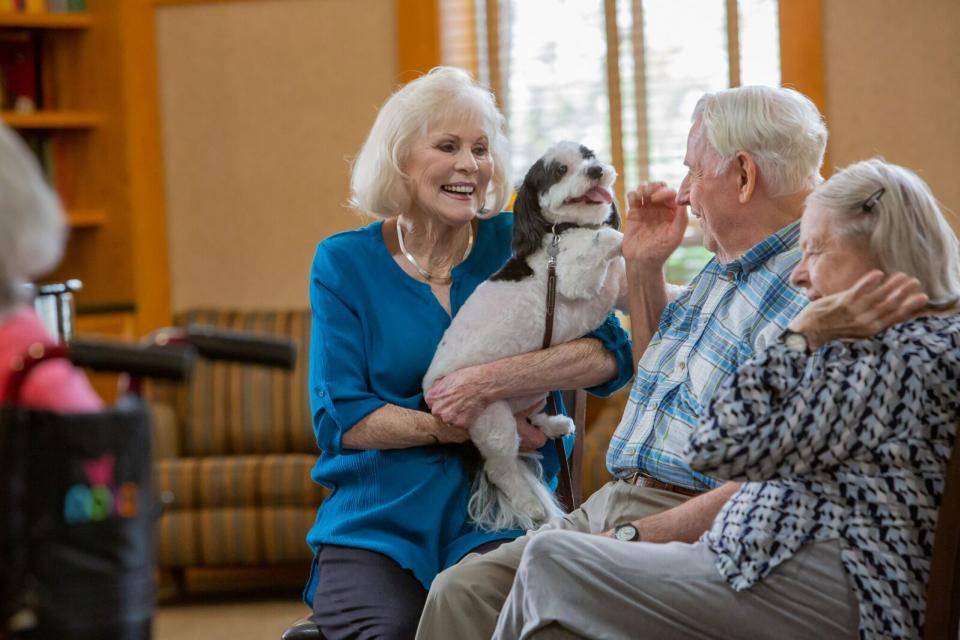 Three residents talking, with one woman holding her dog.