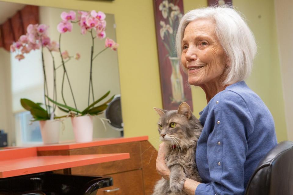 A woman resident sitting on a chair holding her cat in her arms.