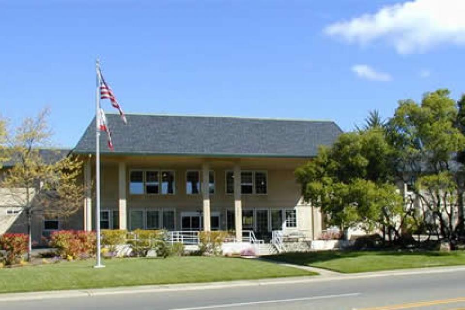 Eskaton Lodge Cameron Park front entrance with grassy lawn, trees and the American flag
