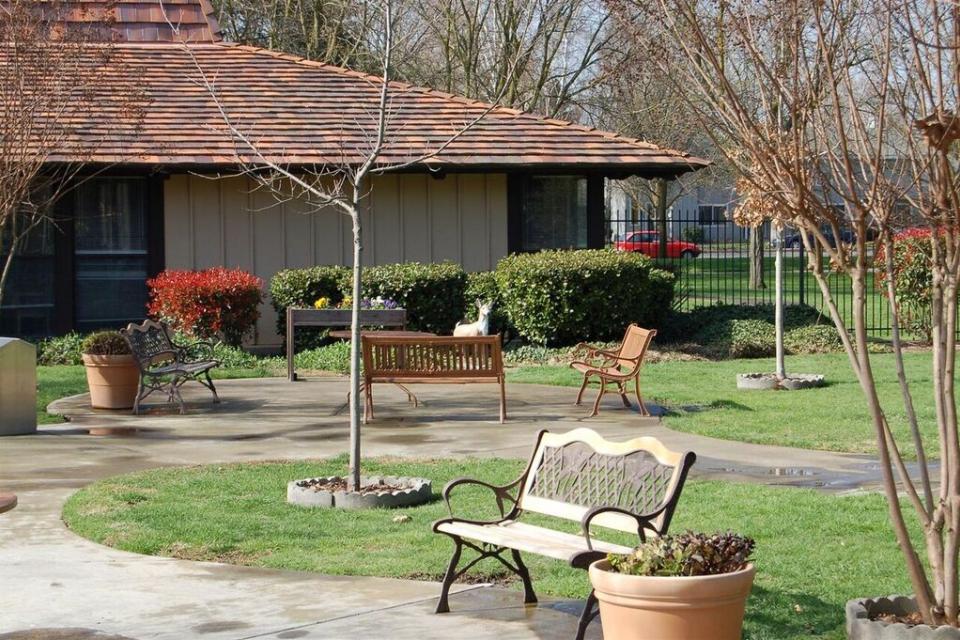 Eskaton Care Center Greenhaven front entrance with beautiful lawn and plans, and a bench. 