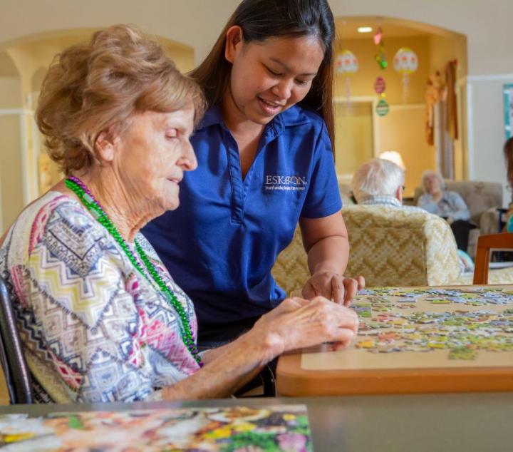 Resident and staff working on a puzzle 