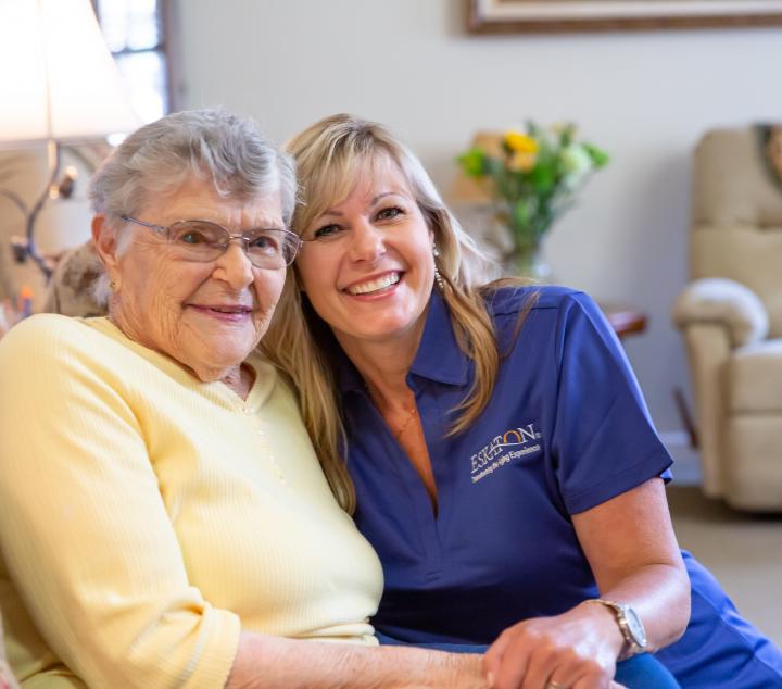 Two women, one a resident and the other a staff member smiling together.