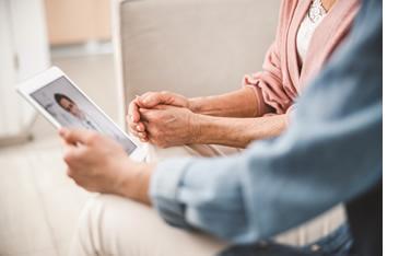 Two women face-timing and talking to a doctor with their iPad.