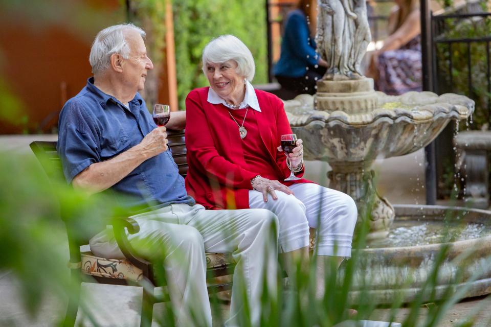 Couple sitting by water fountain enjoying a glass of red wine.