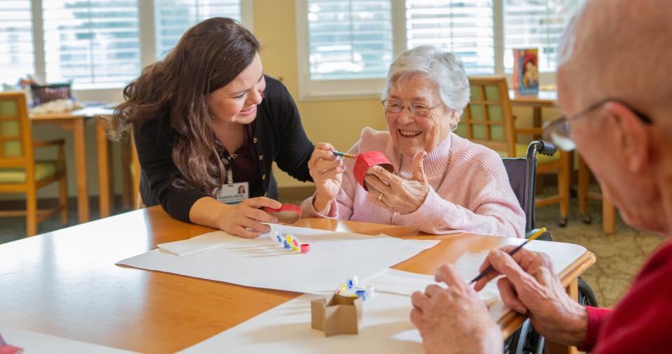 Two residents and on staff member painting painting together.