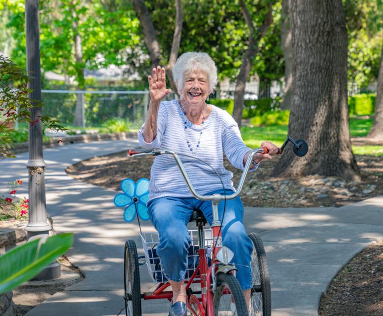 Woman riding a bike, smiling and waving