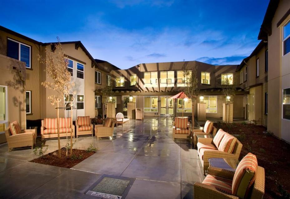 The Parkview patio area with lounge chairs, table, chairs and umbrella, and trees 