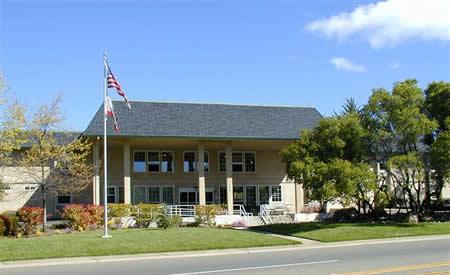 Eskaton Cameron Park front entrance with grassy lawn, trees and the American flag