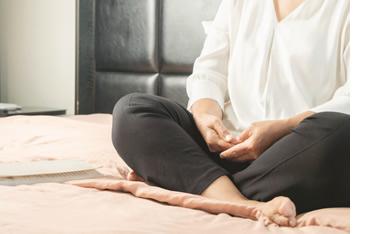 Woman sitting on the floor with her feet crossed, meditating.
