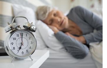 Woman sleeping with her alarm clock on the nightstand