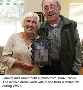 A resident couple smiling and holding a photo of themselves when they were 17 and 19 years old.