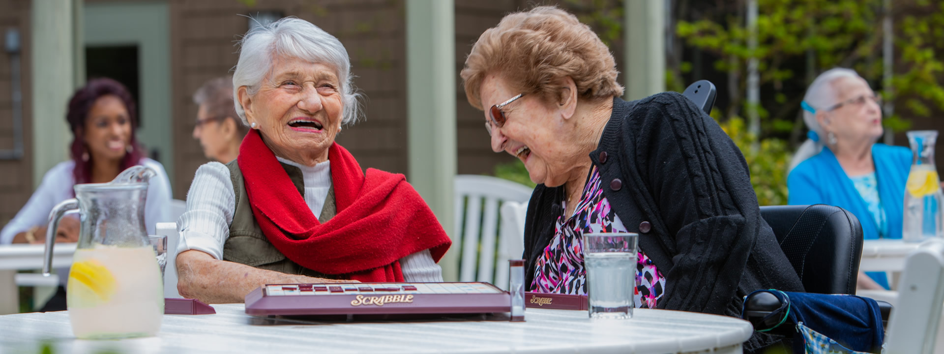 Two women residents having fun playing a game of scrabble on the outdoor patio.